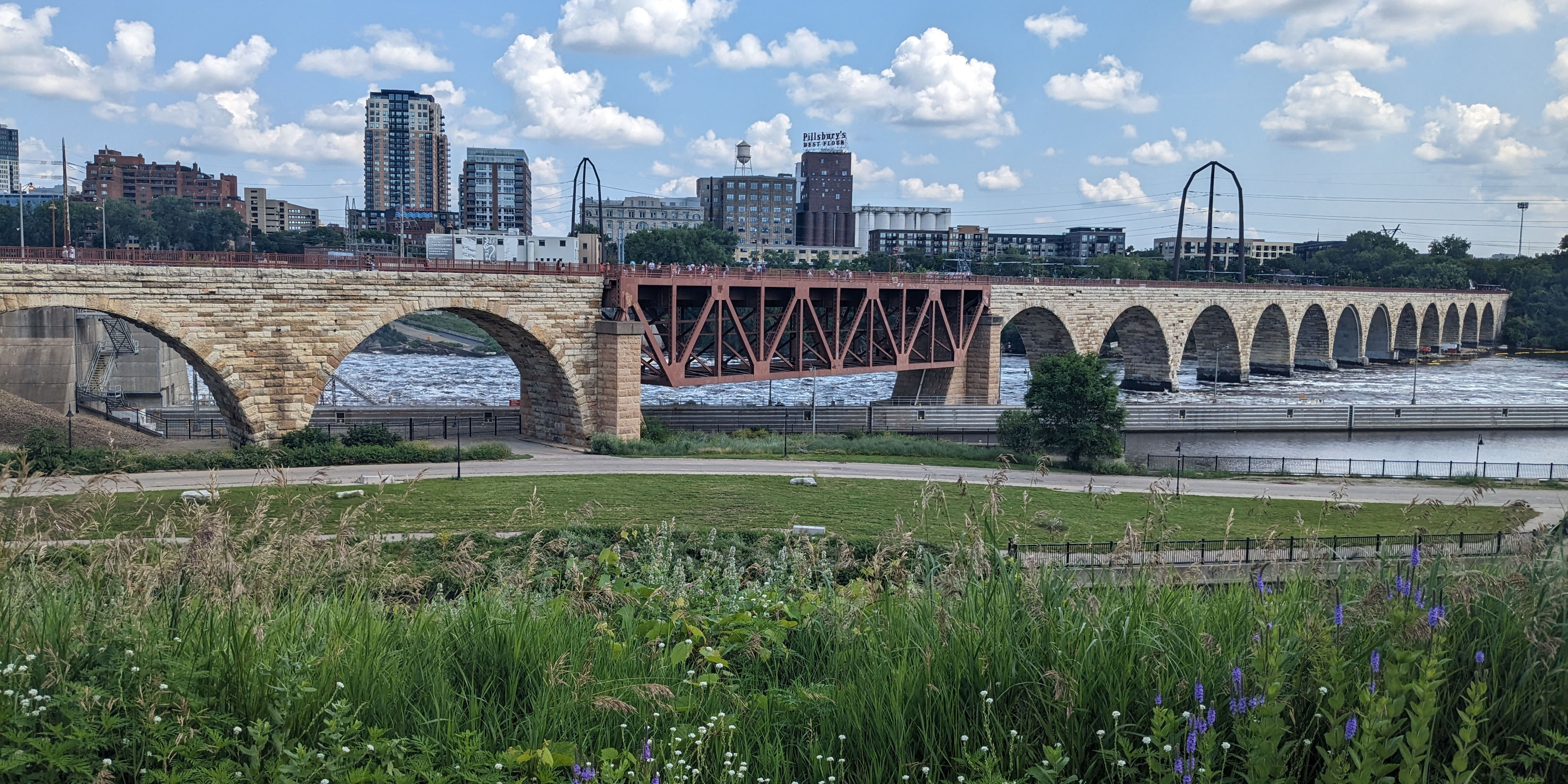a ground view of a bridge from minneapolis going into st paul, with the skyline in the background 
